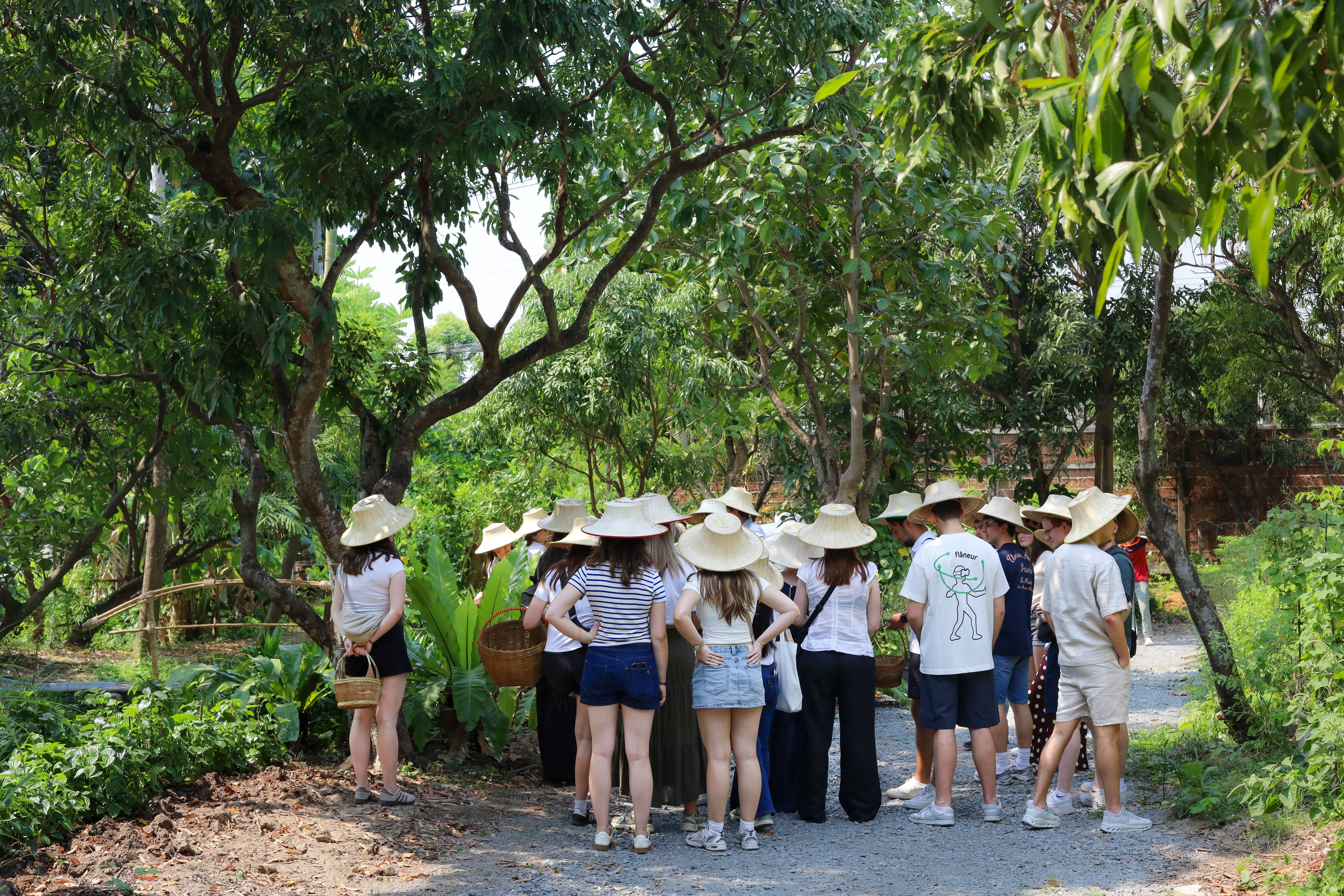 A guide leading a group through Poomjai Garden's permaculture beds and hanging Spanish moss.