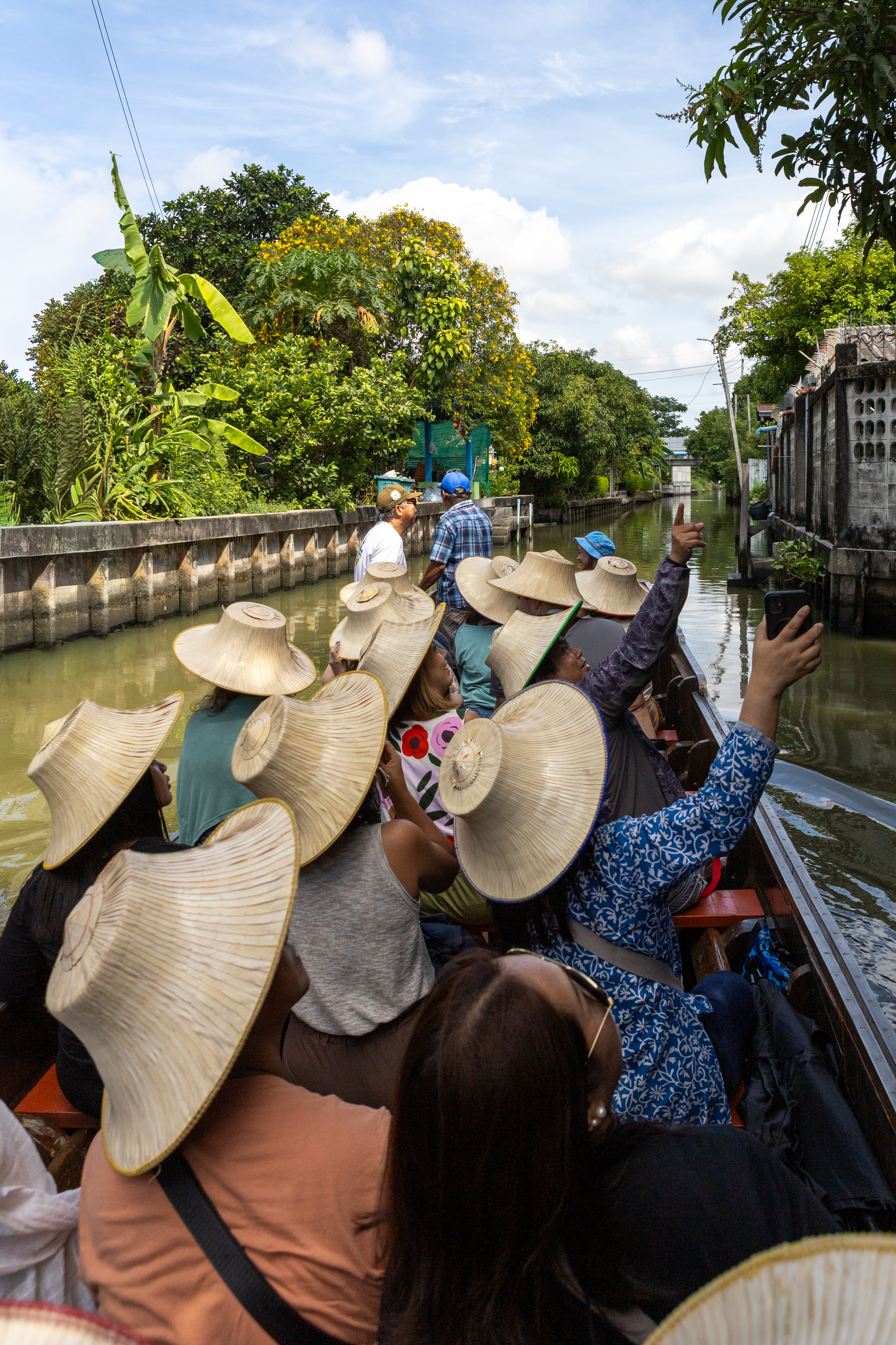 A tour group riding a longtail boat along the canal, pointing out sights along the way.