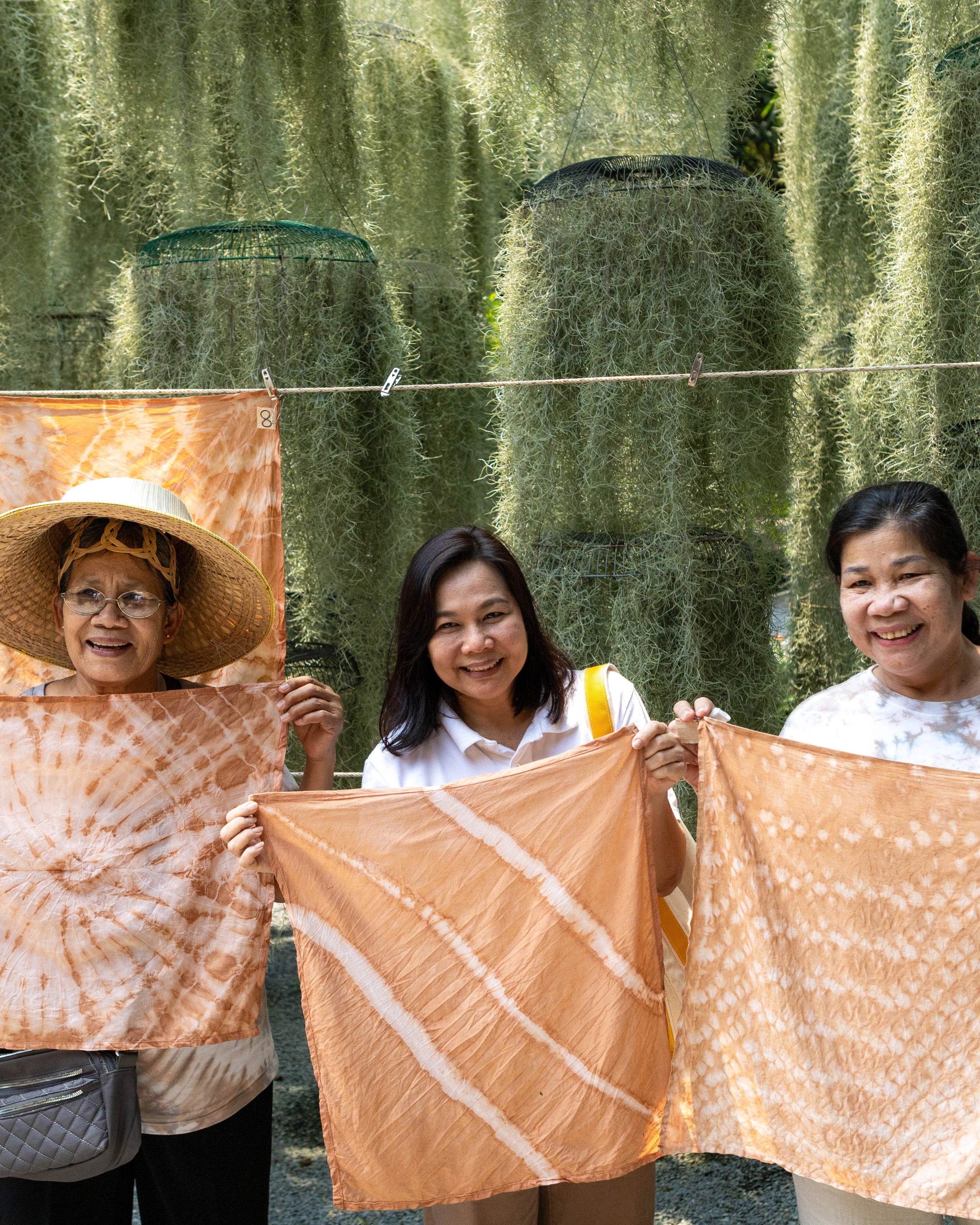 Guests holding up their finished shibori tie-dye cloths after the workshop.