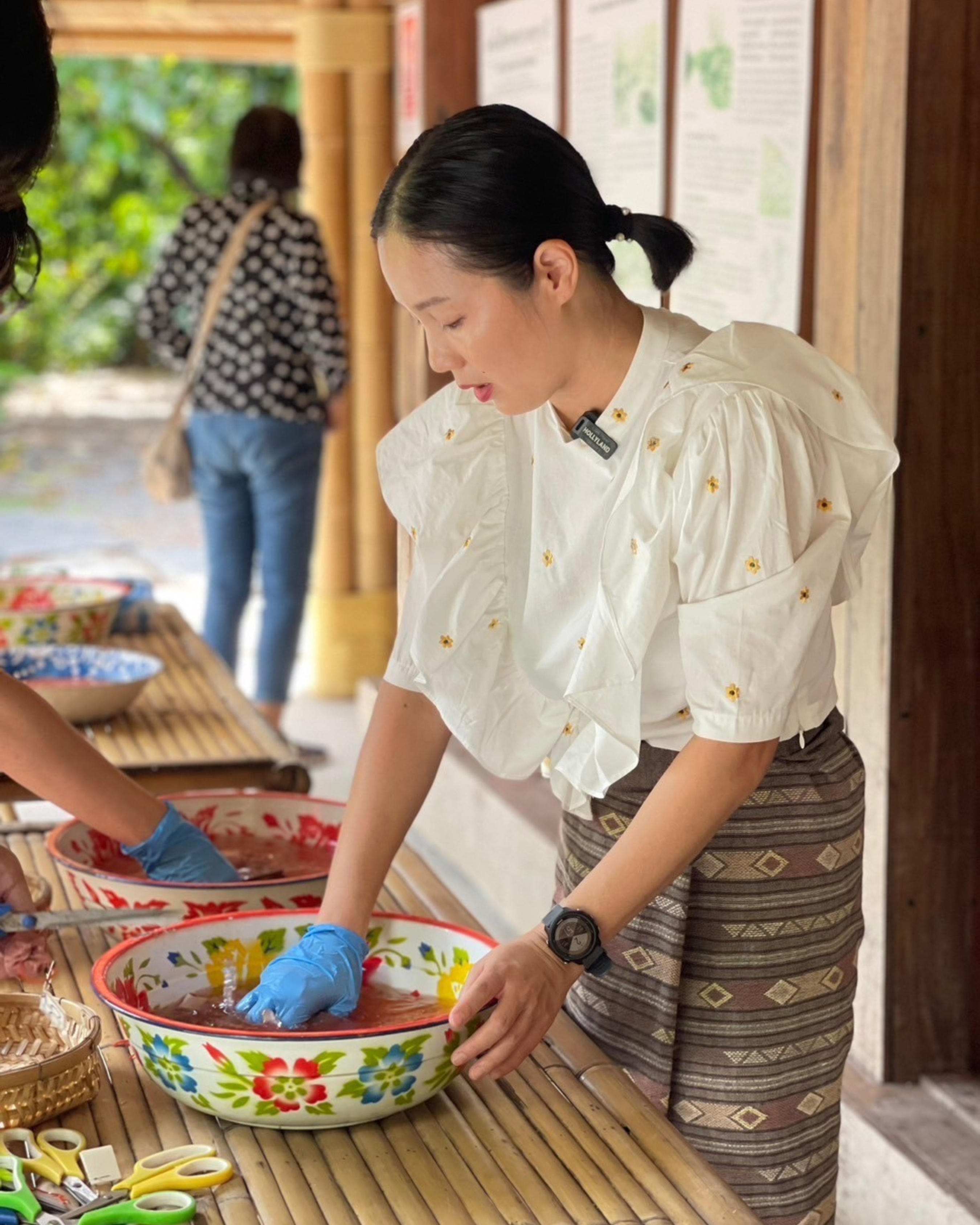 A guide dipping tied fabric into a bowl of natural dye during the workshop.