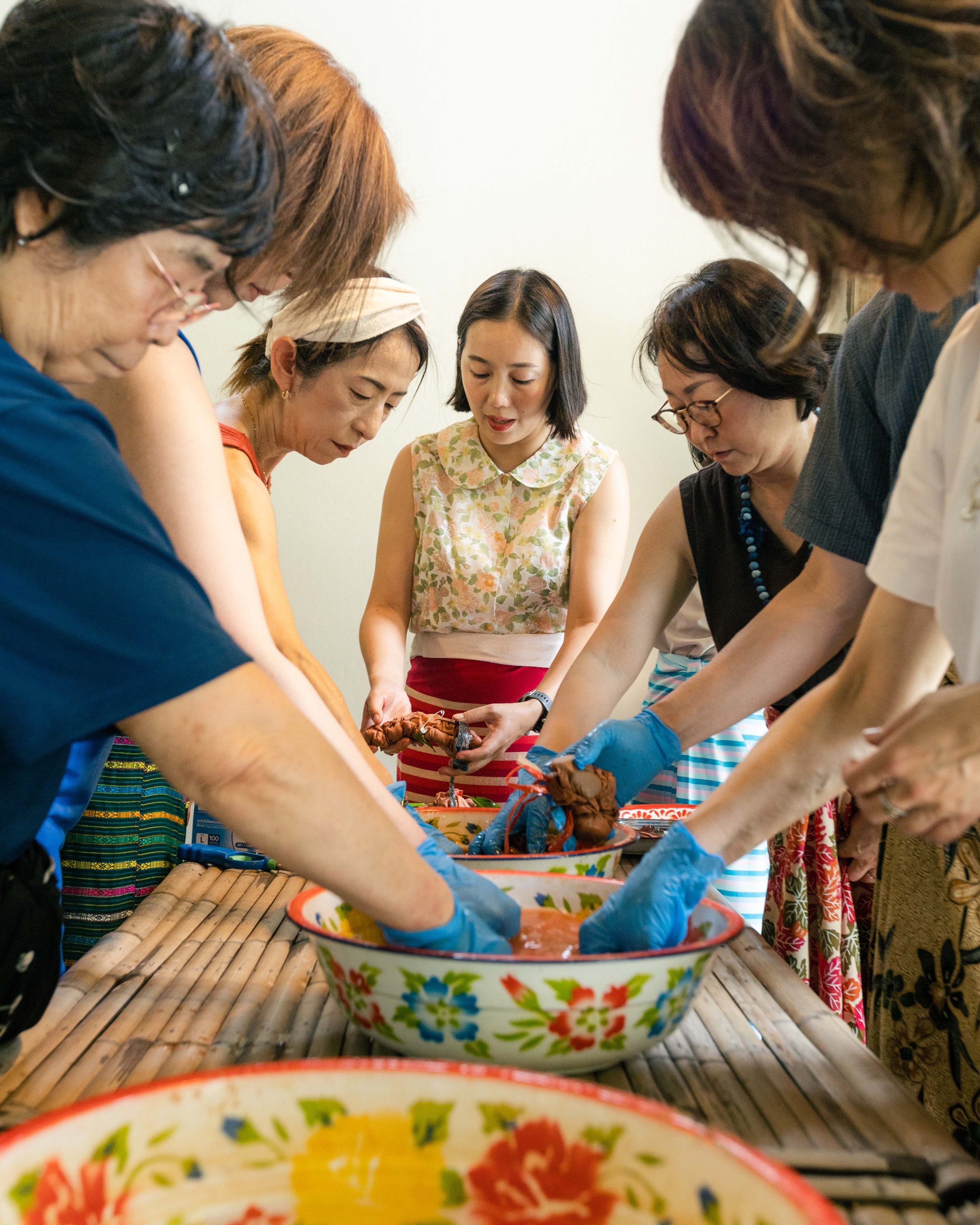 Several guests dipping their tied fabric into bowls of natural dye together.