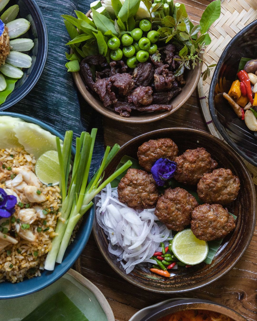 A flat-lay of Thai dishes including grilled beef salad and crab fried rice at Natura Caf&eacute;.